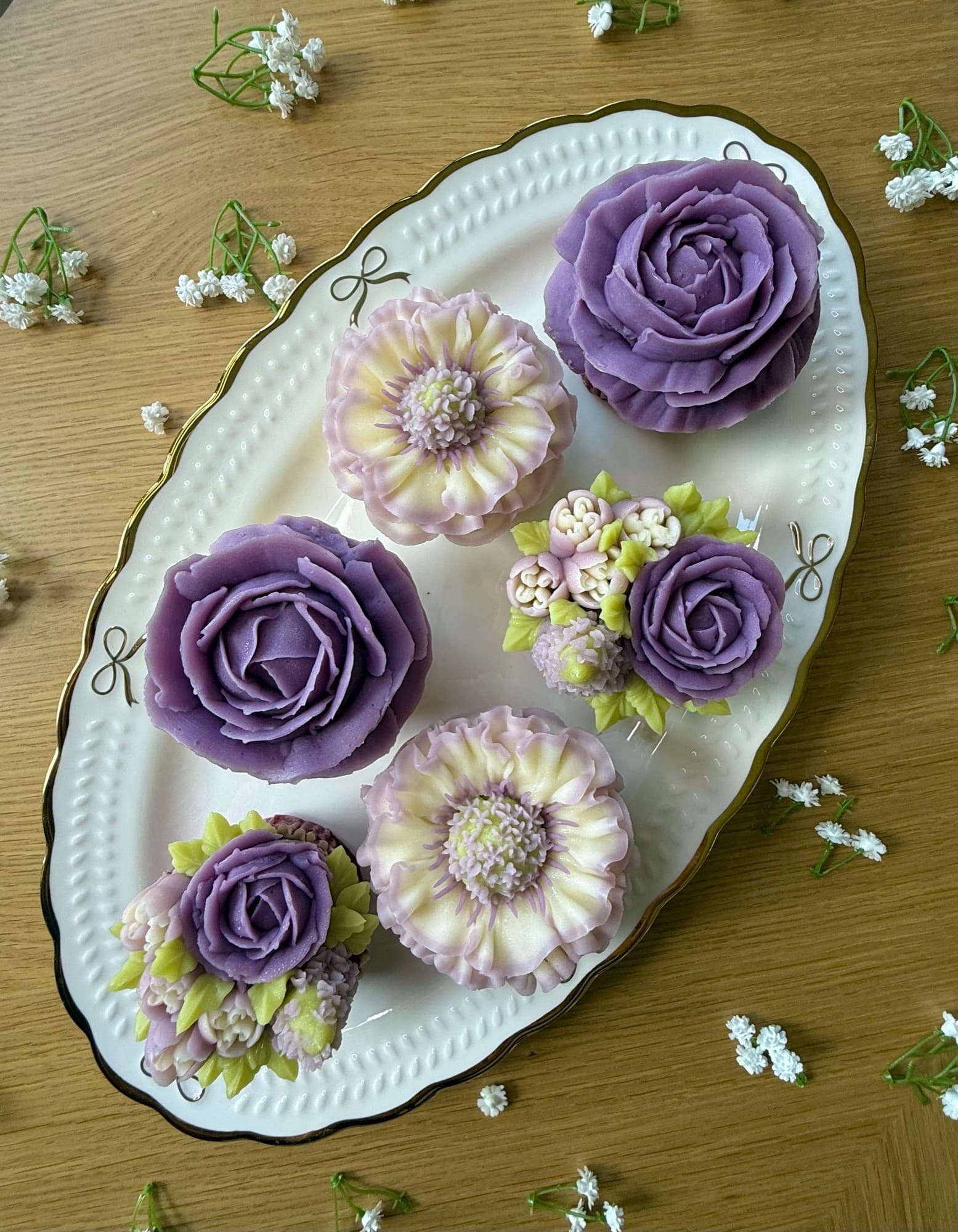 Lavender roses and cream floral cupcakes on a white oval platter